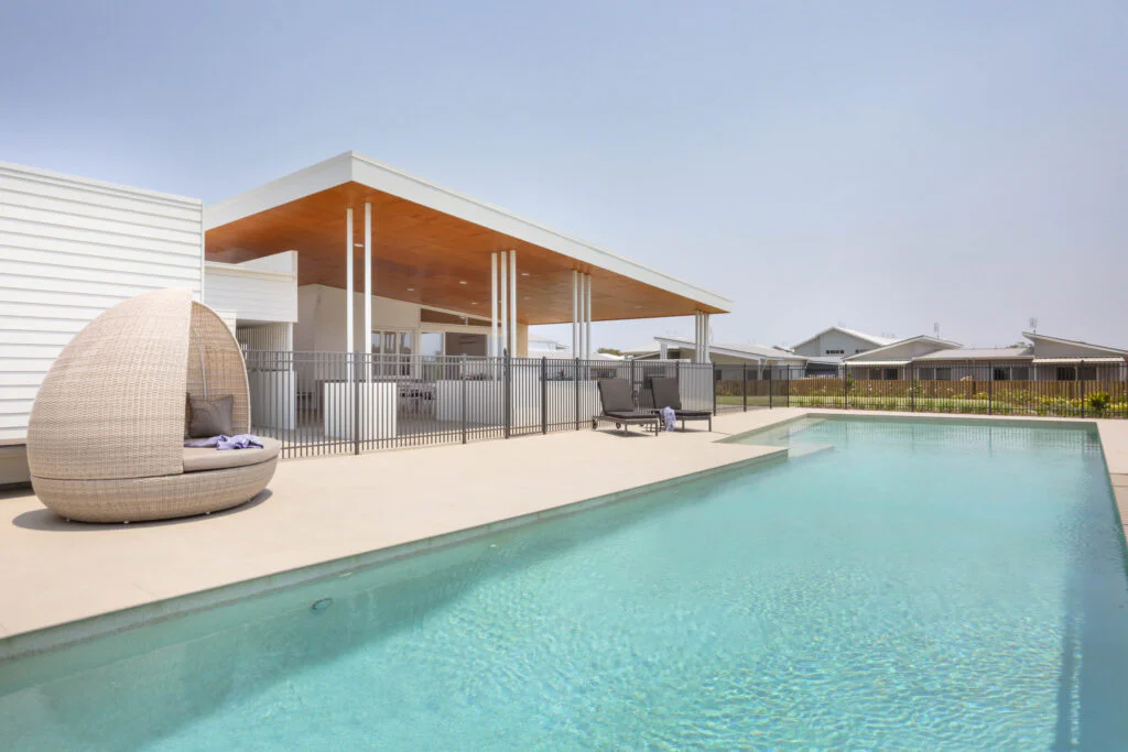 Outdoor swimming pool with pool fence and outdoor furniture.