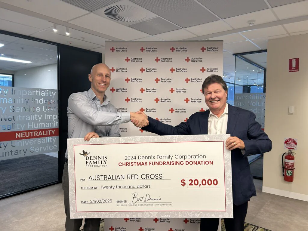 Two people inside holding a large donation cheque