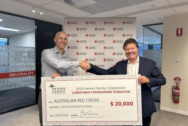 Two people inside holding a large donation cheque