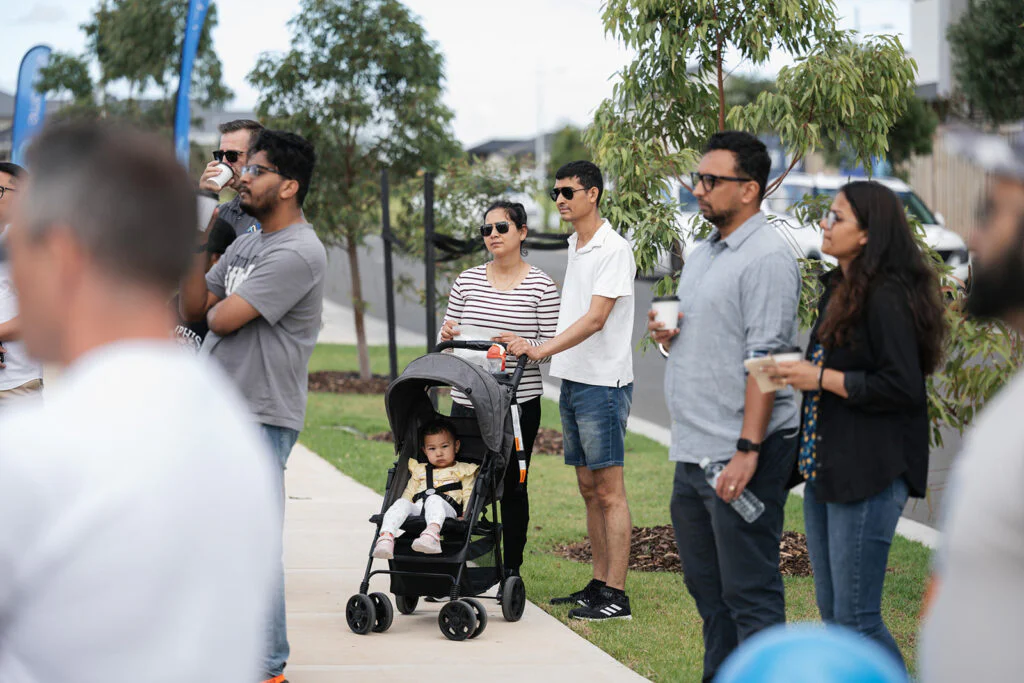 People standing on a footpath casually watching an event