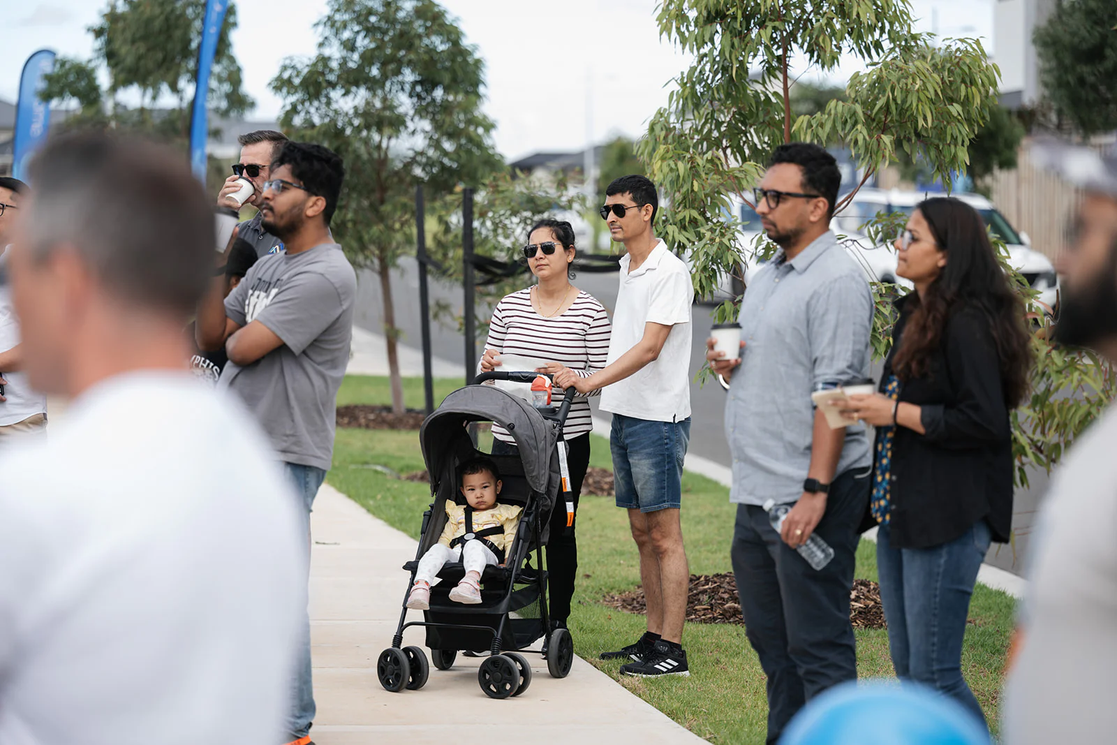 People standing on a footpath casually watching an event